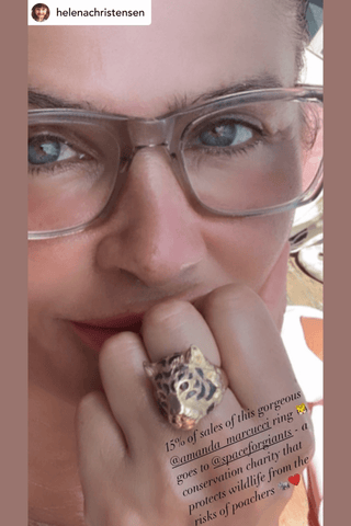 Close-up of a person wearing glasses with a focus on their hand and ring.