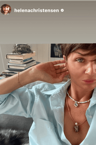 Woman wearing a light blue shirt and pearl necklace with a neutral background