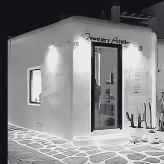Jewelry Atelier storefront with illuminated sign and cacti on a stone pavement